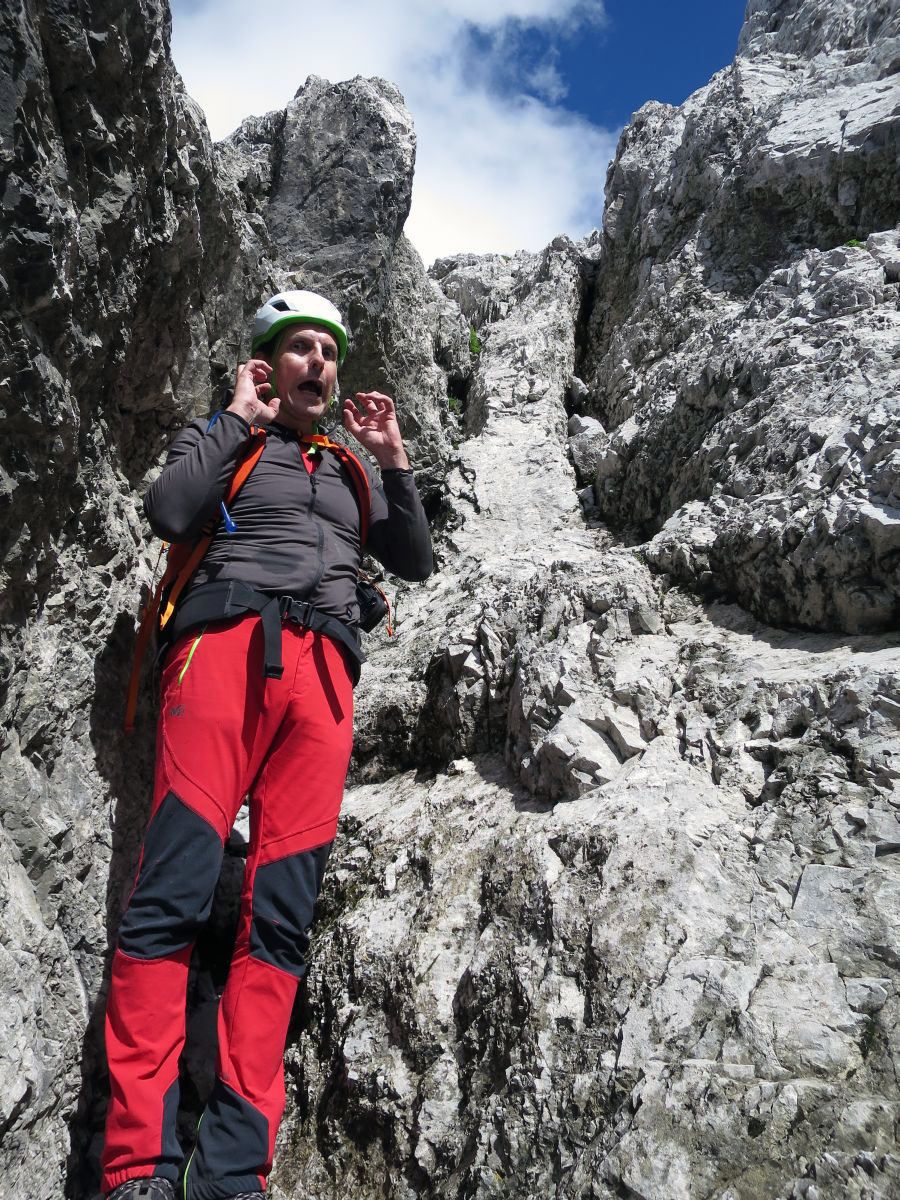 lali084.JPG - In der Hauptrinne lauert weiter oben eine ziemlich fiese 3m hohe Stufe. Es gibt nur zwei vernünftige Griffe und zwei Pflicht-Tritte, bei denen man von oben seine Füße kaum sieht, weil man eine Rippe umarmen muss, an deren Spitze der beste Griff (groß, aber glatt) ist. Den will man auch unbedingt haben und erst loslassen, wenn unten wirklich alles perfekt passt. Links und rechts ist nur glattes Glump. Im Abstieg ein ziemlicher Horror. Für Kurze eigentlich gar nicht machbar und gefährlich. Man kann sich nicht einfach an Henkeln runterlassen und mit den Füßen rudern bis was kommt. Wir sind beide über 1.85 und das hat so grad mal gelangt für die Pflicht-Tritte. Oberhalb der Rinne sind zwei nagelneue Schlaghaken angebracht. Wer ein 25m Reepschnürl dabei hat, kann sich wenigstens an was herunterlassen. Das ist die einzige wirklich haarige Stelle in der Tour. Man kann hier zwar nicht den ganzen Berg runterdonnern, aber es ist darunter abschüssig und blockig. Rauskippen oder abspringen ist keine Option!